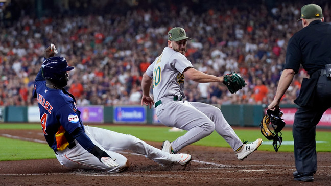 Houston Astros' Yordan Alvarez, left, scores as Oakland Athletics relief pitcher Sam Moll, right, covers home plate after throwing a wild pitch during the sixth inning of a baseball game Sunday, May 21, 2023, in Houston. (AP Photo/David J. Phillip)
