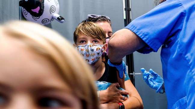 FILE - Finn Washburn, 9, receives an injection of the Pfizer-BioNTech COVID-19 vaccine in San Jose, Calif., on Nov. 3, 2021, as his sister, Piper Washburn, 6, waits her turn. California's COVID-19 emergency declaration ends on Tuesday, Feb. 28, 2023. Public health experts say the pandemic has not ended, but the virus is much more manageable with the availability of vaccines and other treatments. (AP Photo/Noah Berger, File)
