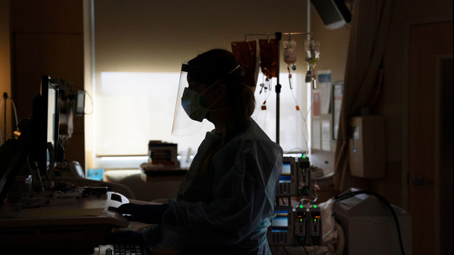 FILE - A registered nurse works on a computer while assisting a COVID-19 patient in Los Angeles. (AP Photo/Jae C. Hong, File)