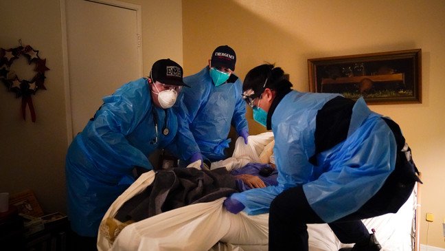 Emergency medical workers Jacob Magoon, from left, Joshua Hammond and Thomas Hoang lift a patient onto a gurney in Placentia, Calif., on Jan. 9, 2021. (AP Photo/Jae C. Hong, File)