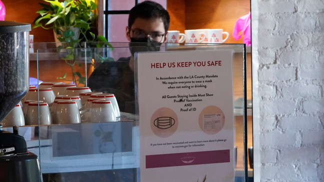 FILE - A sign explaining the LA County Mandate is posted for customers inside the Intelligentsia Coffee on Sunset Blvd., in Los Angeles, Monday, Nov. 29, 2021. (AP Photo/Damian Dovarganes)