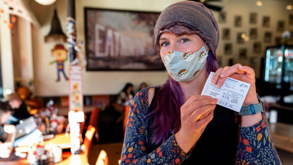 FILE - Melanie Bolen, a personal trainer, shows her vaccination card before being allowed to sit inside the Fred 62 restaurant in the Los Feliz neighborhood of Los Angeles, Monday, Nov. 29, 2021. (AP Photo/Damian Dovarganes)