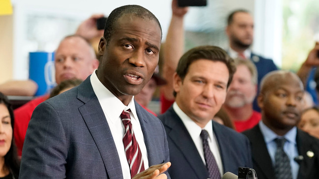 FILE - Florida Surgeon General Dr. Joseph Ladapo, front left, gestures as speaks to supporters and members of the media before a bill signing by Gov. Ron DeSantis, front right, Nov. 18, 2021, in Brandon, Fla. (AP Photo/Chris O'Meara, File)