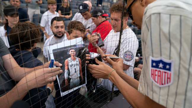Victor Wembanyama, a projected first round 2023 NBA draft prospect, signs autographs before throwing the ceremonial first pitch before a baseball game between the New York Yankees and the Seattle Mariners, Tuesday, June 20, 2023, in New York. (AP Photo/John Minchillo)
